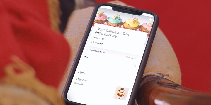 Corgi holding an IPhone using the UberEats application to order cake