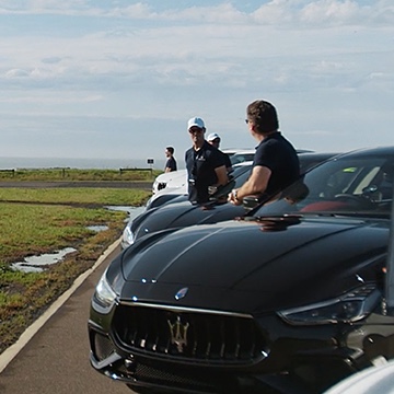 Men waiting beside black Maserati sports cars