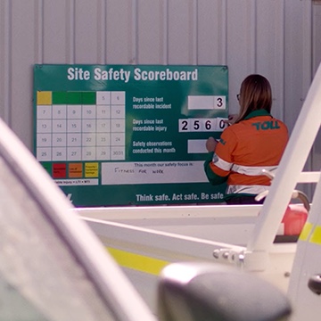 Photograph of a female employee in uniform updating the Site Safety Scoreboard