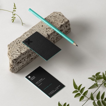 Simple photo of Xavier Knight Business card and a pencil carefully placed on a stone with leaves around it