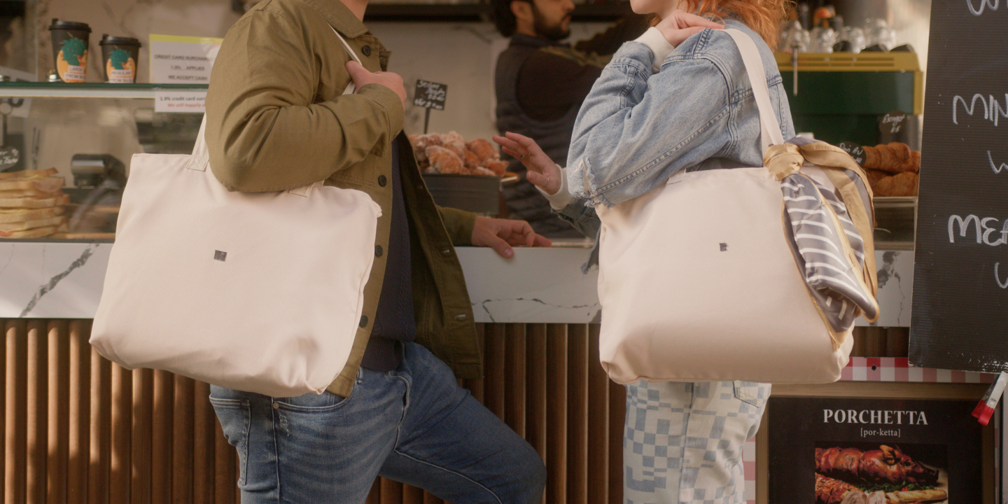 Two tote bags on owners shoulders at coffee shop in the LIV Munro campaign video