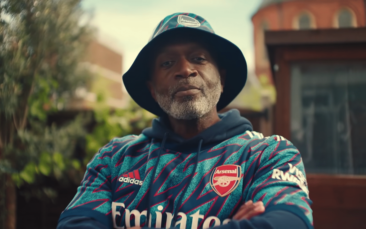 Man arms crossed with bucket hat and Arsenal FC kit